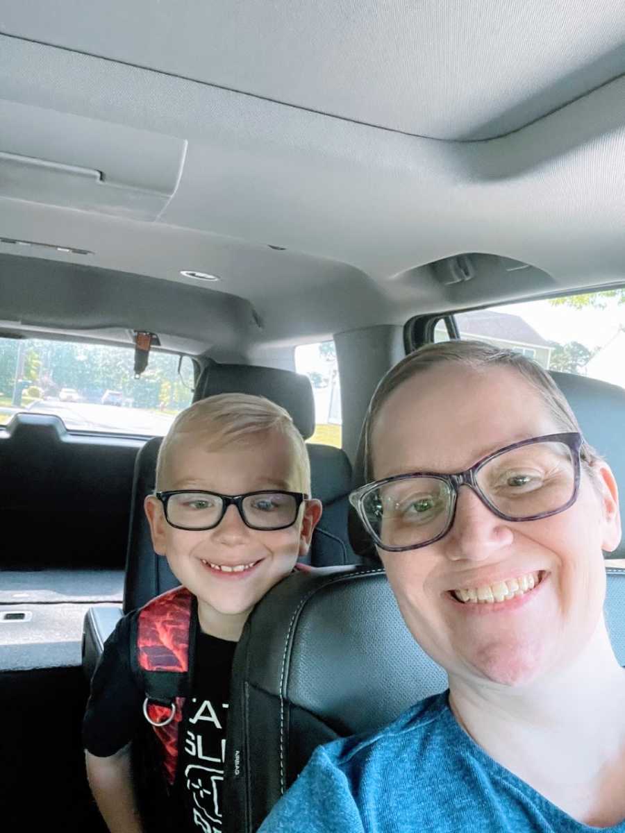 Woman takes a car selfie with her son, both wearing glasses