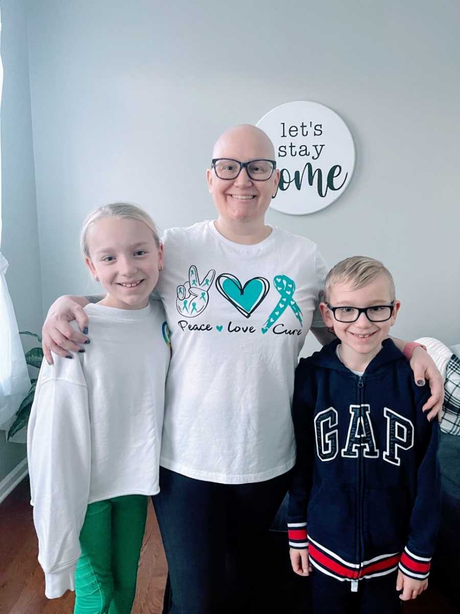 Mom takes a photo with her two kids after she shaves her head due to hair loss from cancer