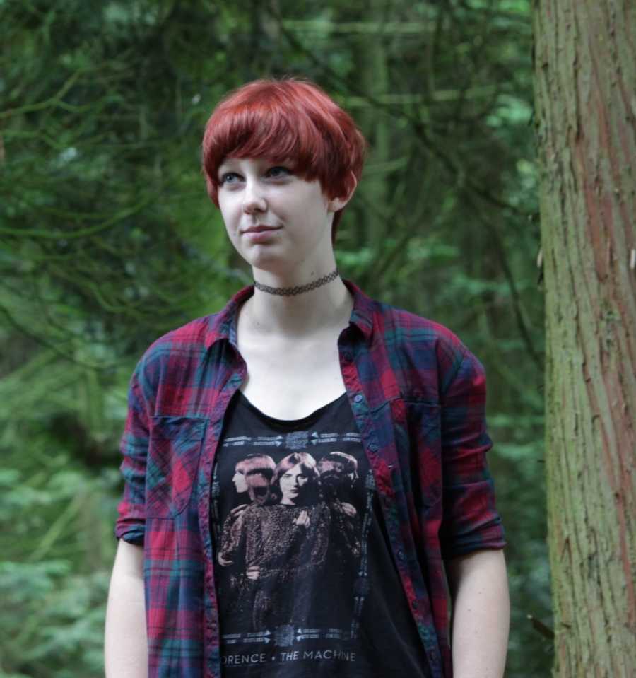 person standing in forest in a flannel, red hair