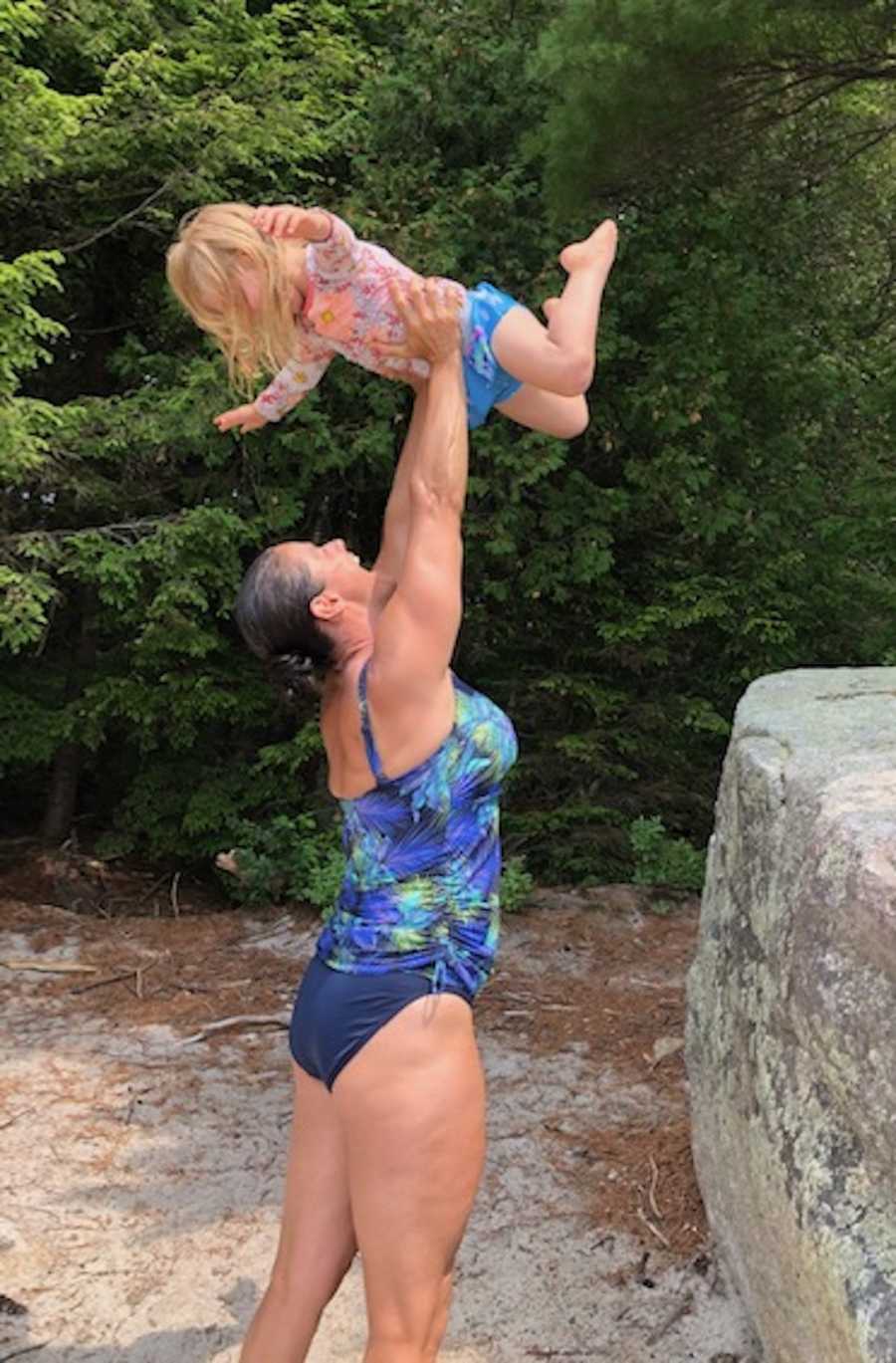 woman in bathing suit holding her kid up