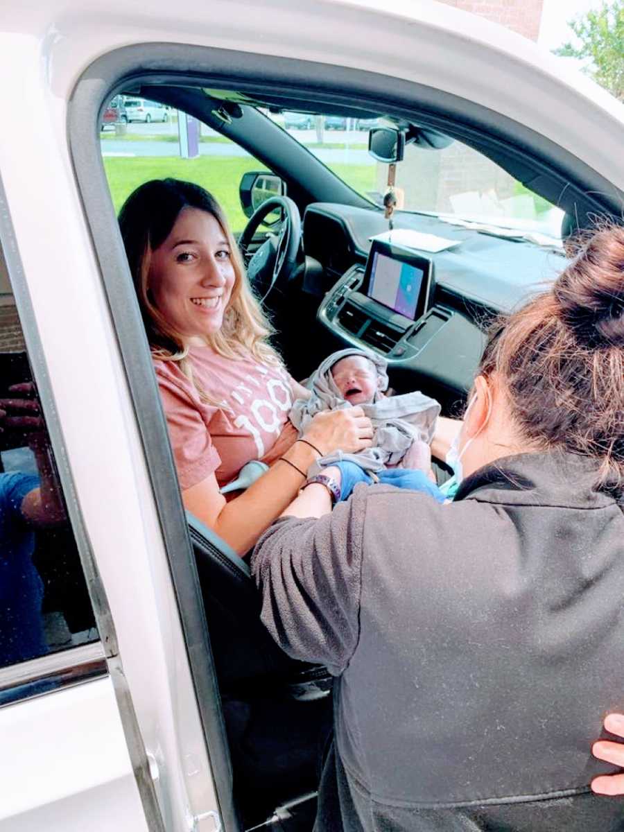 Woman smiles while holding her newborn baby girl in the car she just delivered her in