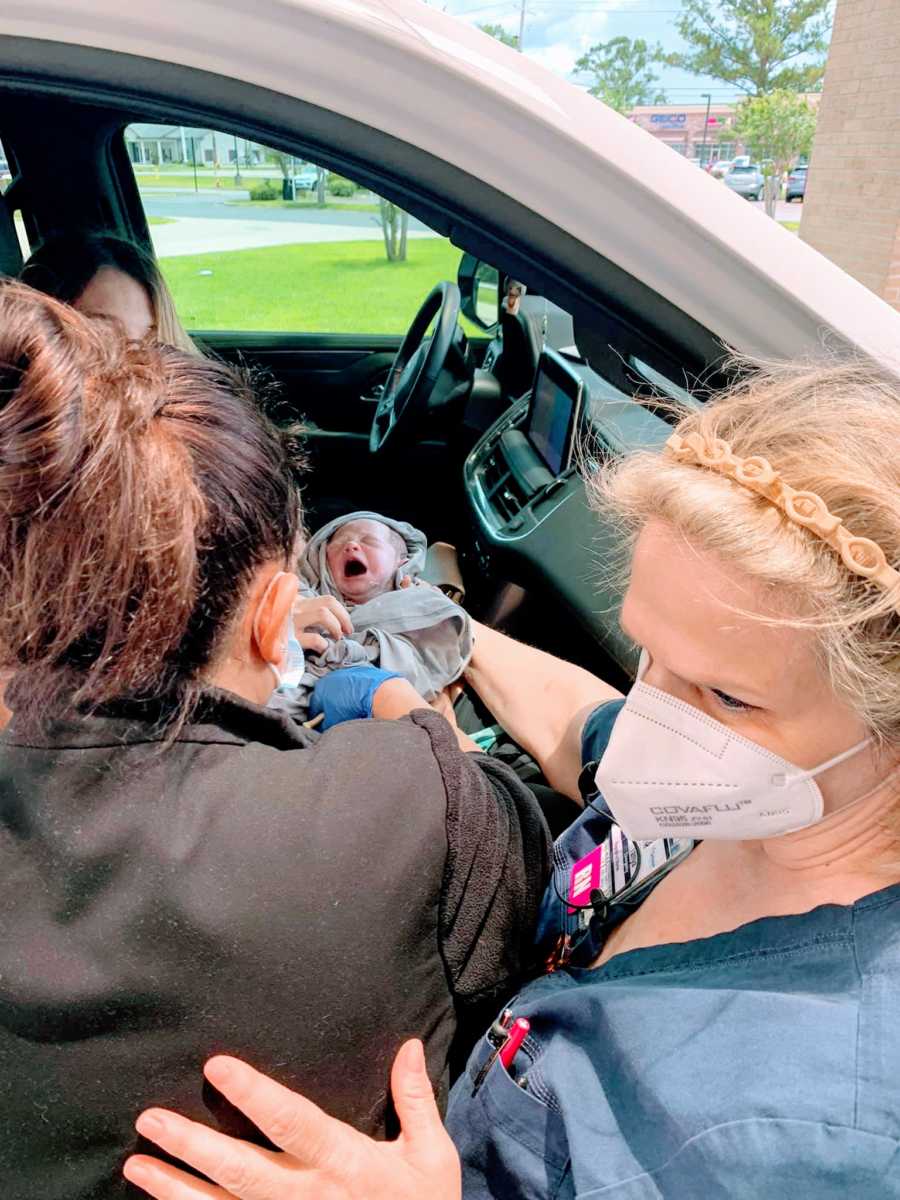 Mom sits in her car with newborn baby girl she just delivered while ER nurses check her vitals