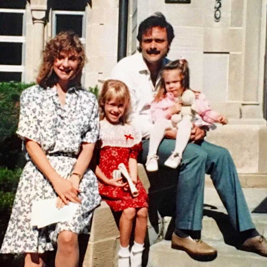 Family of four sitting on front steps smiling