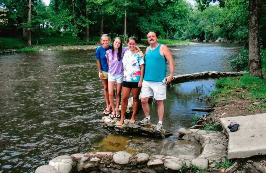 Family of four standing on rocks by water