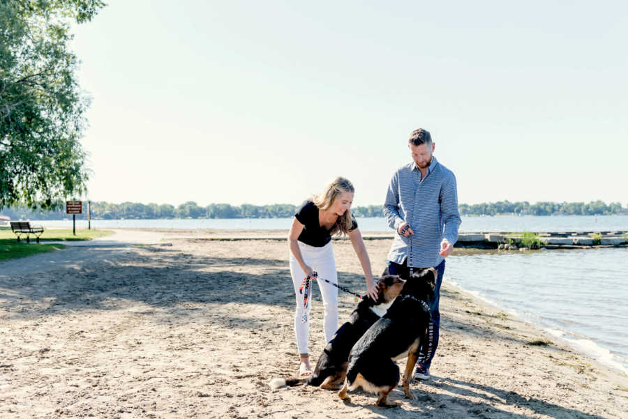 Husband and wife with two dogs on leashes at beach