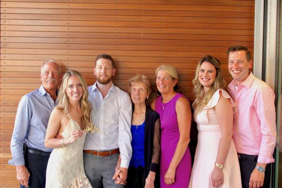 Wedding photo of bride and groom with family in front of wood-slatted wall