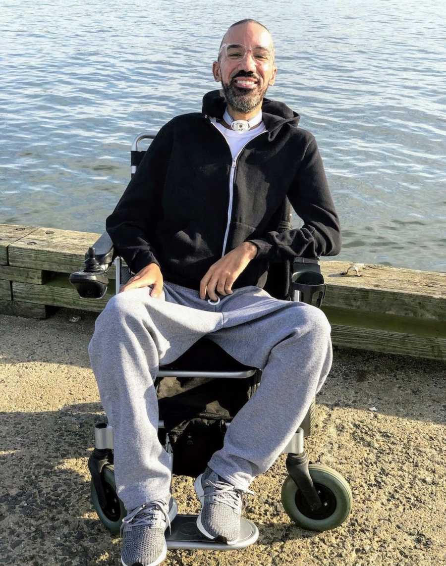 Man in wheelchair by lake smiling