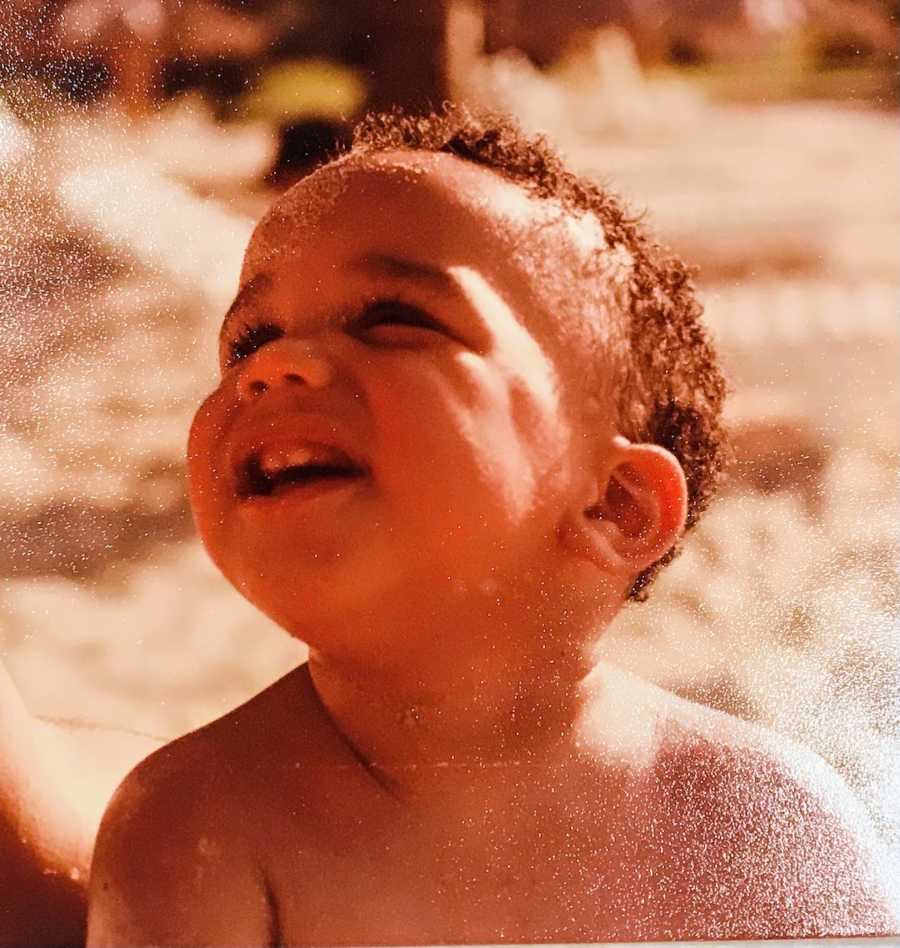 Baby boy sitting outside looking up at sky