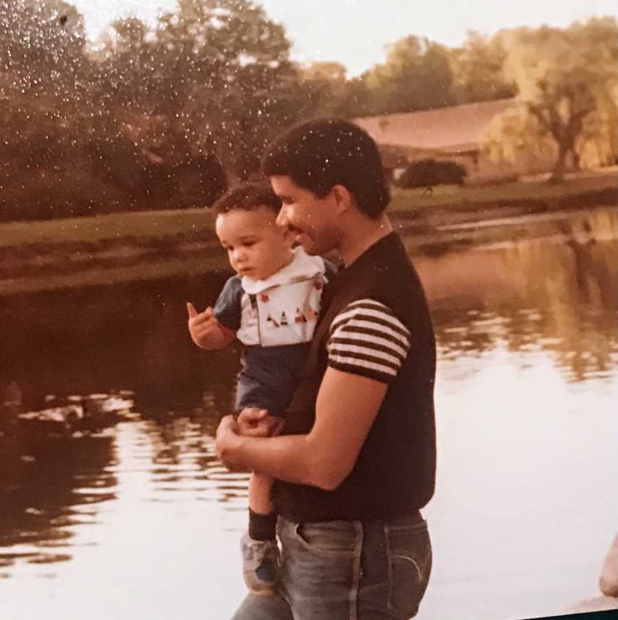 Father holding young son by lake