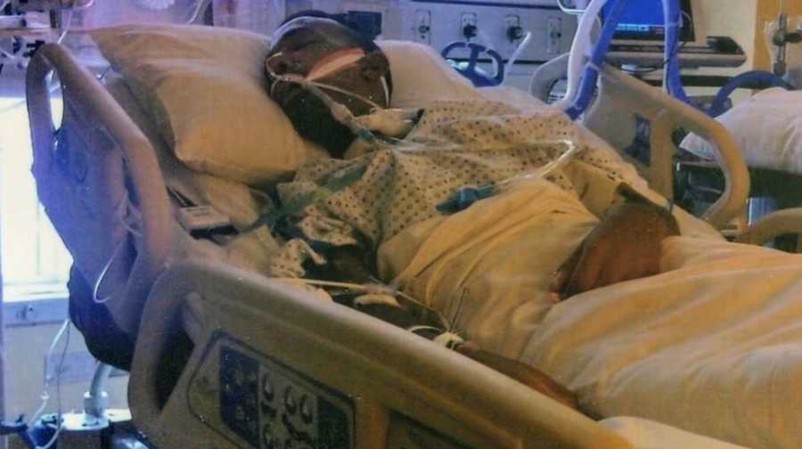 Man lying in hospital bed hooked up to machines