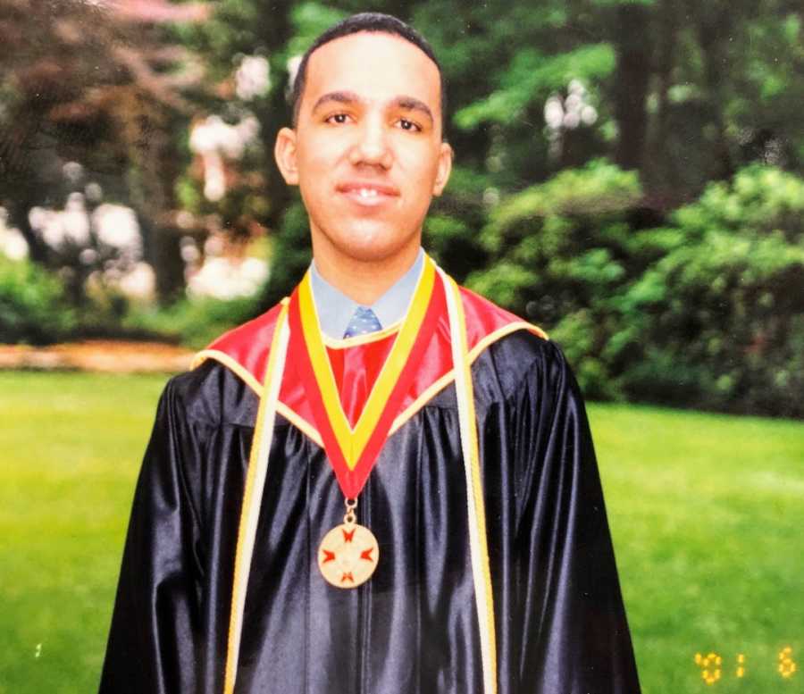 College graduate wearing regalia smiling outside