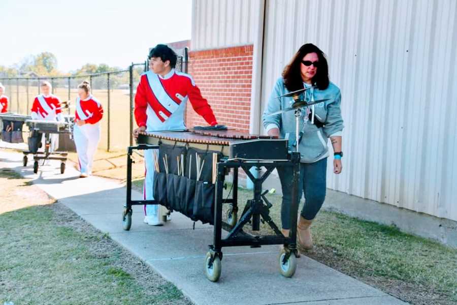 Mom helps her high school son push his instrument for a marching band performance 