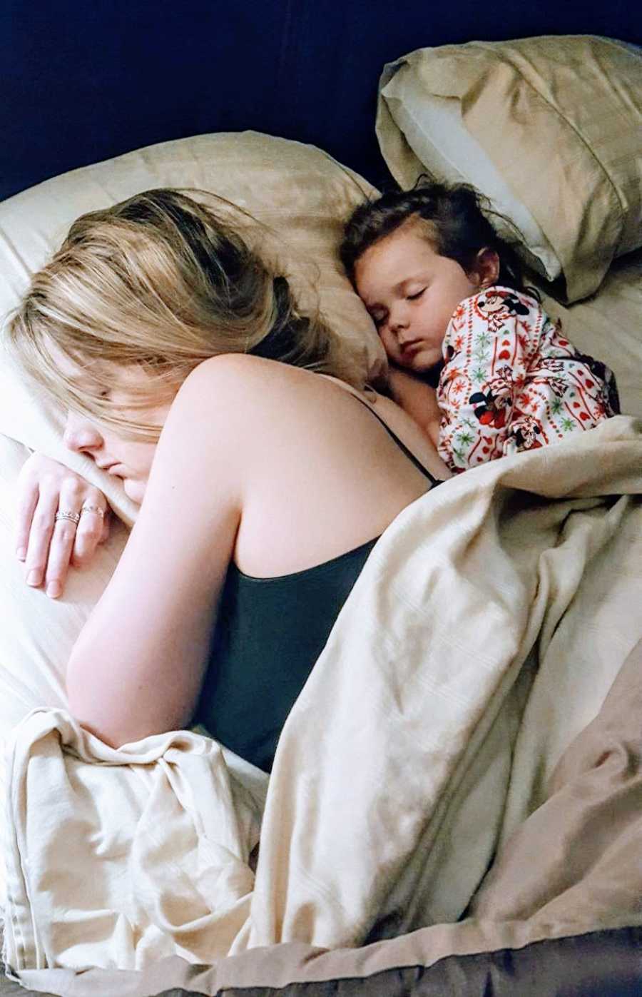 Mom shares a pillow with her daughter while they both sleep after a long day