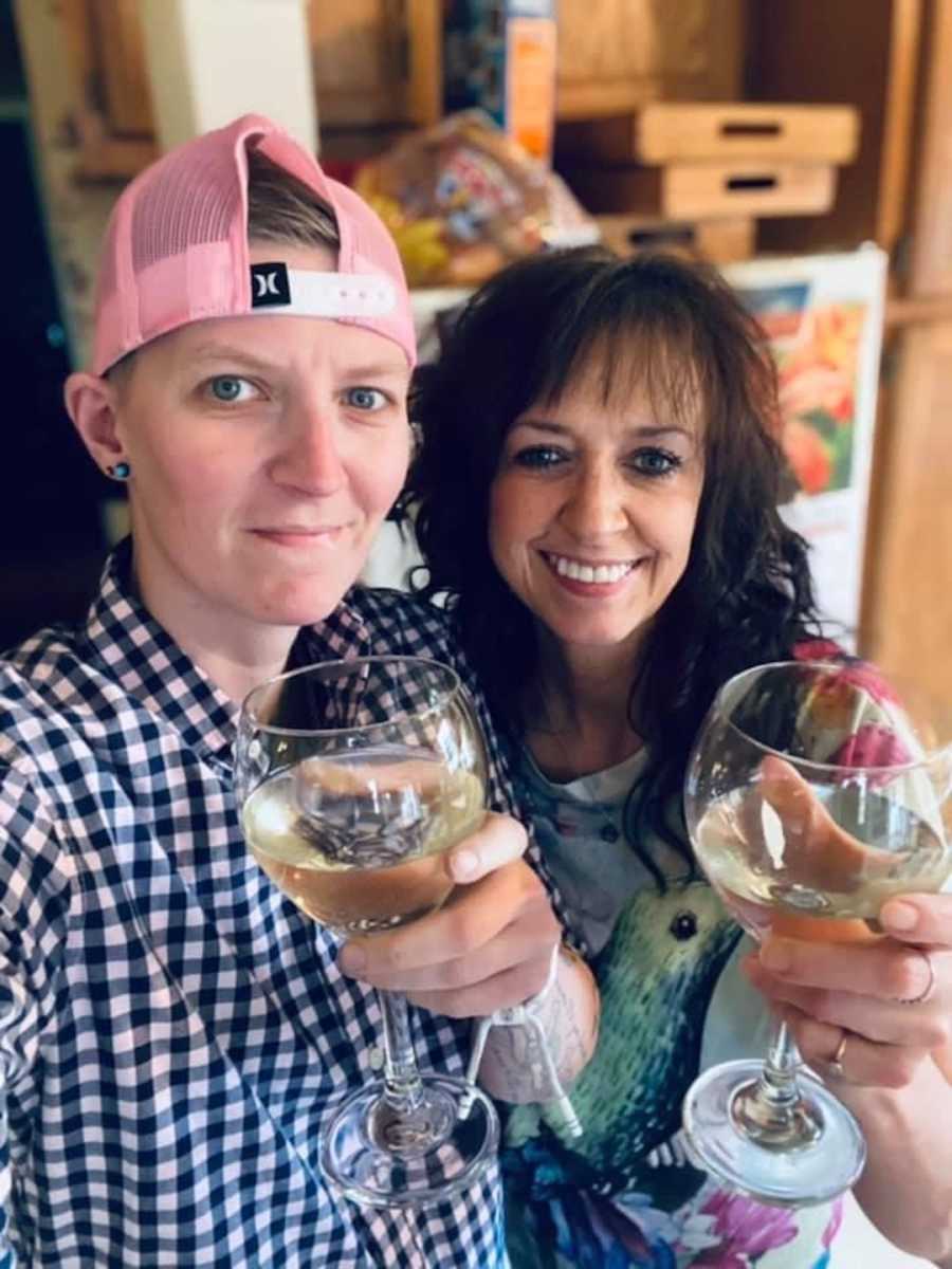 person in baseball cap holding wine glass, woman holding wine glass