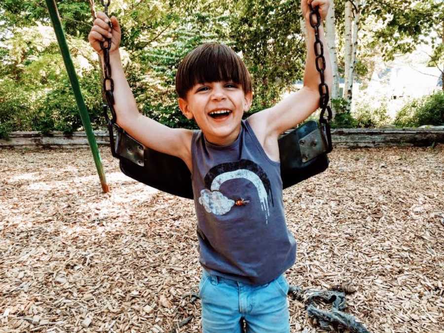 Child at playground on swingset smiling