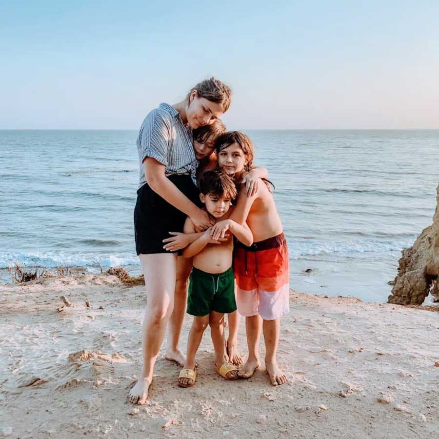 Mother hugging her three children at the beach