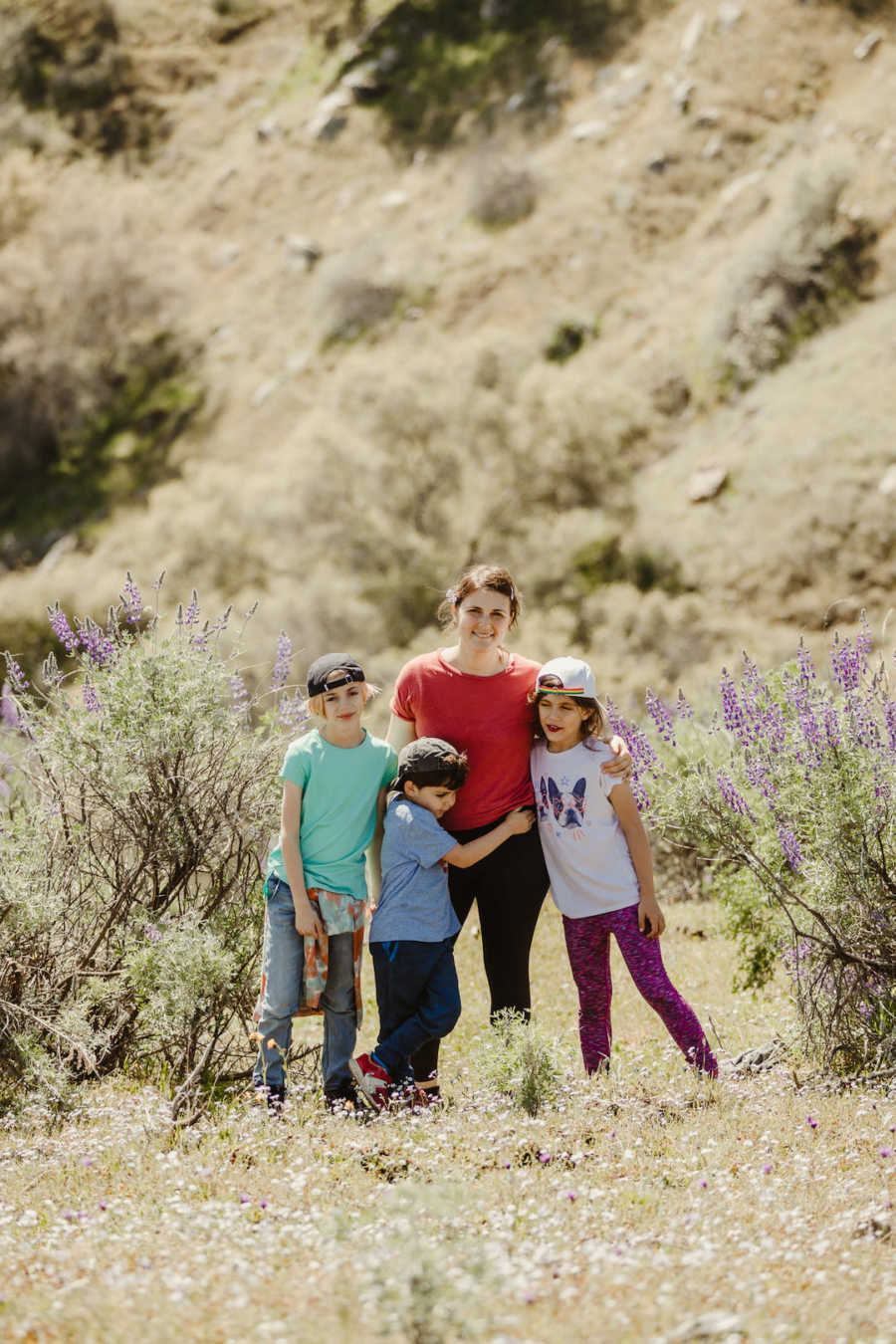 Mother with arms around three children outside