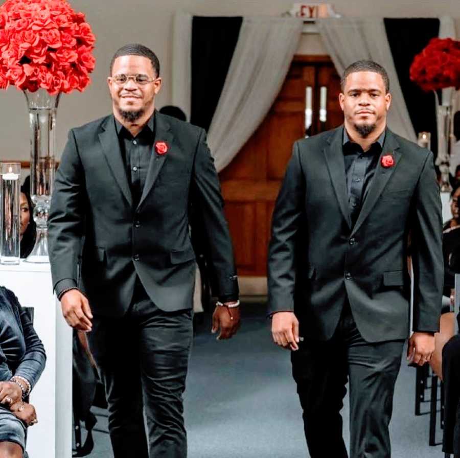 Twin brothers in matching suits get candid photo at an event