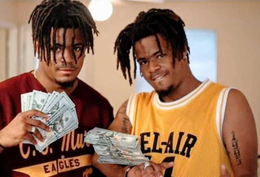 Twins going through a rough patch pose with a bunch of hundred dollar bills