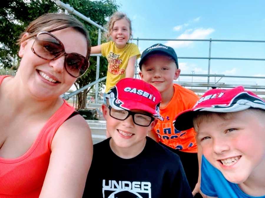 Mom takes a selfie with her kids and step kids while sitting in the bleachers