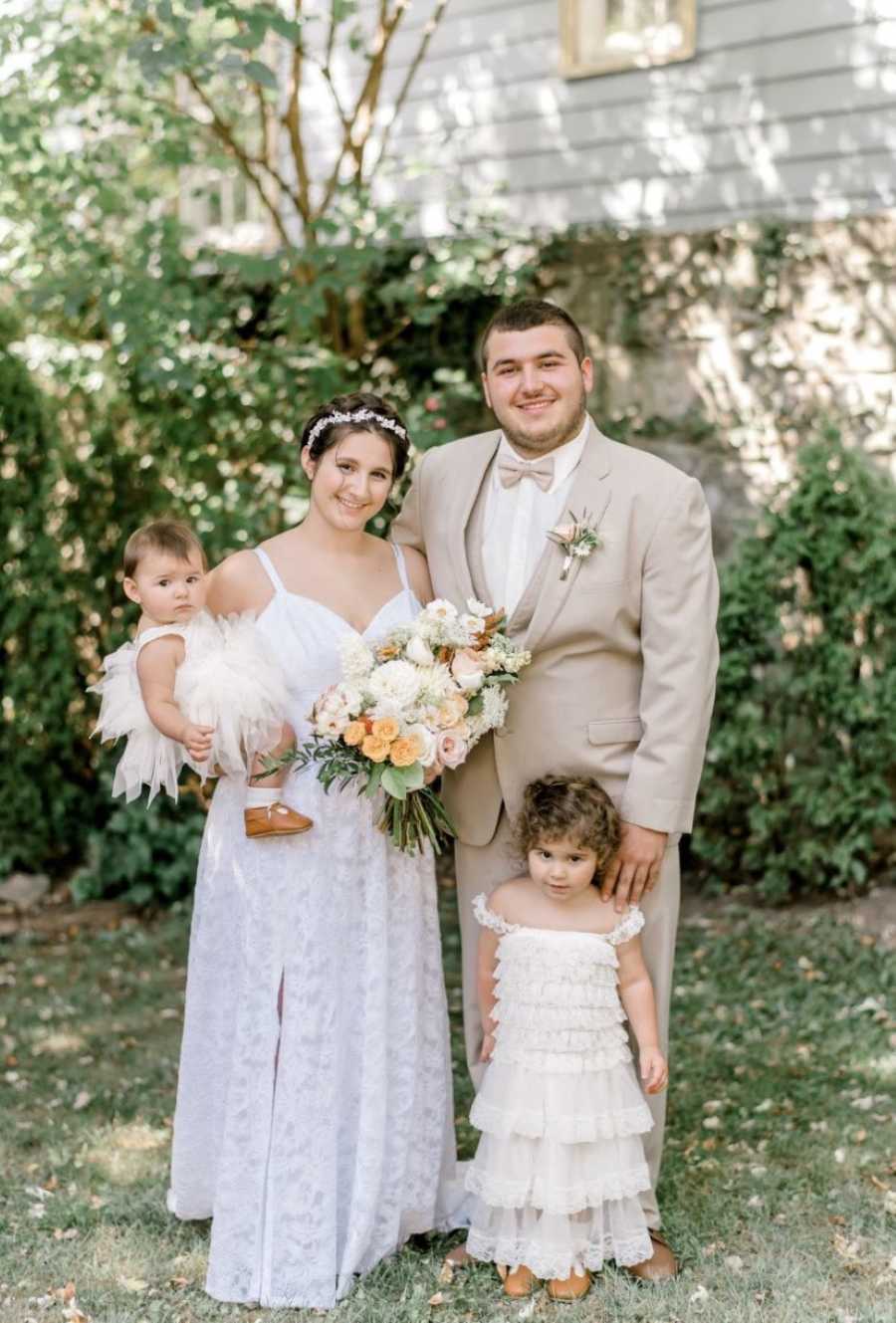 Young couple take family photo at their wedding with their two daughters