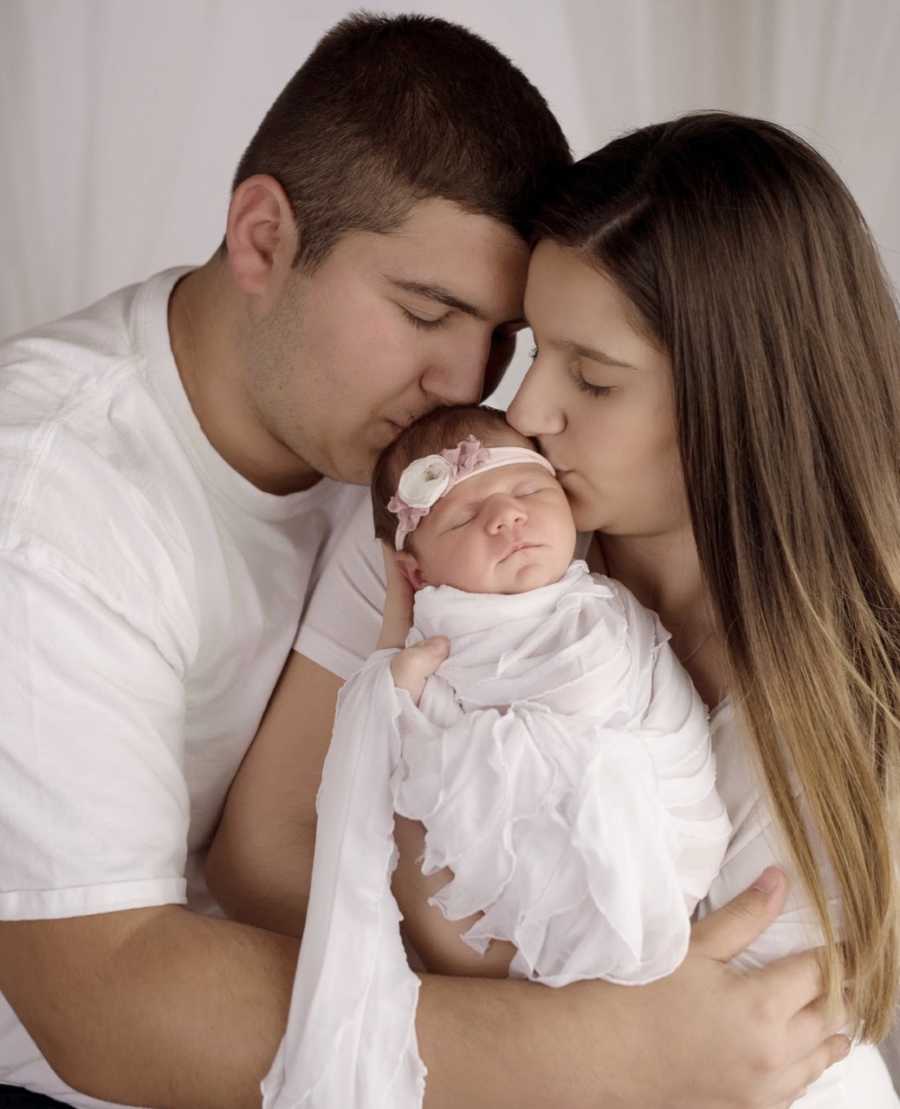 Teen couple take photo with their newborn daughter wrapped in a white blanket