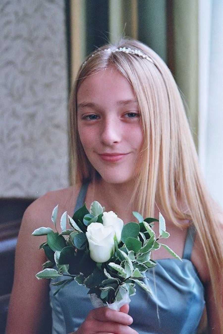 young girl smiling, holding a bouquet of flowers