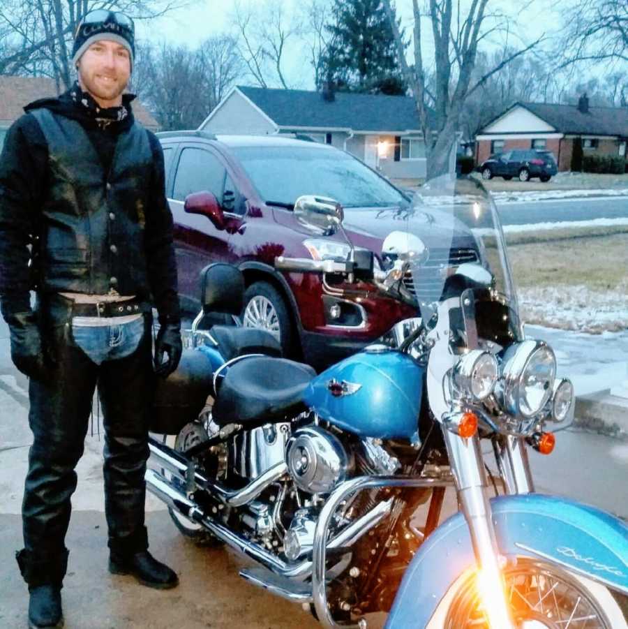 Man wears leather outfit next to his Harley Davidson motorcycle