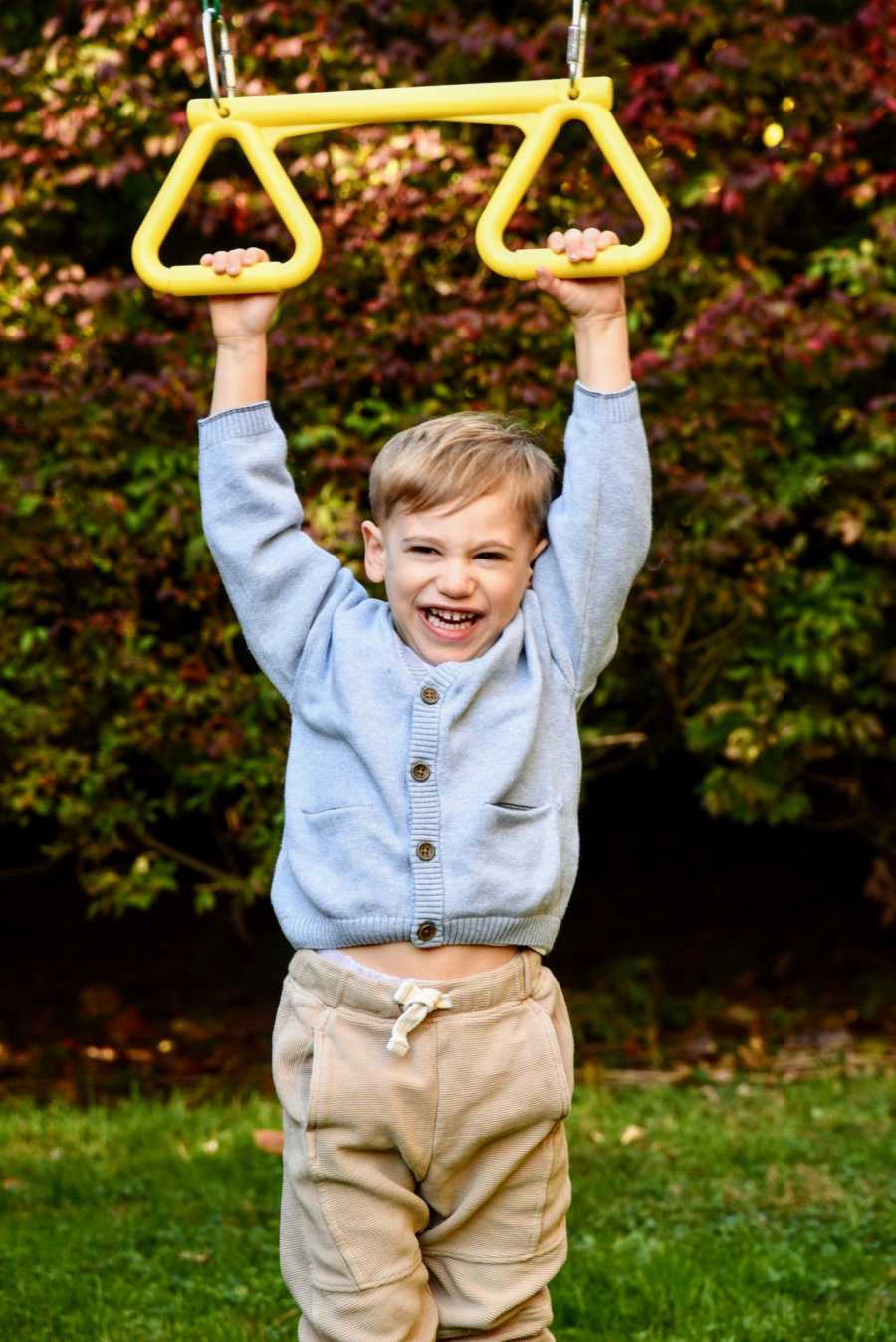 Young boy with CMT smiles and giggles as he plays on a playground