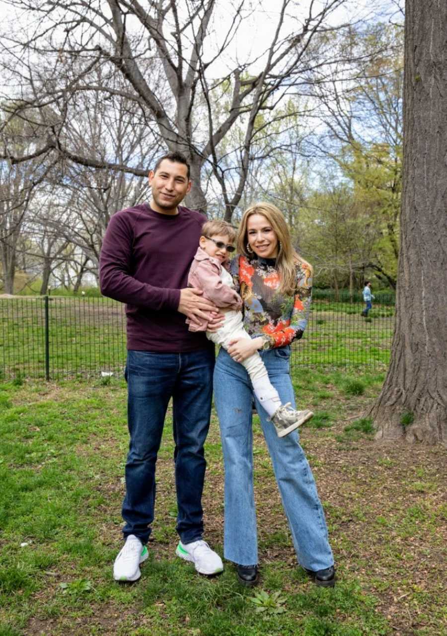 Mom and dad hold son with CMT while taking photos in the park