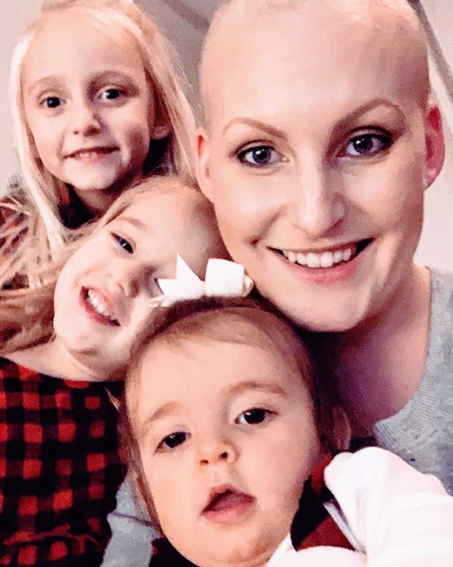 Woman with triple negative breast cancer takes a smiling selfie with her three daughters