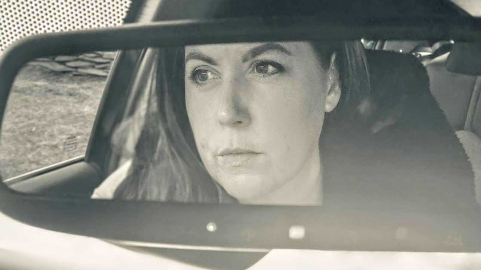 Woman takes a moody selfie in the rearview mirror of her car while reflecting on her inner self