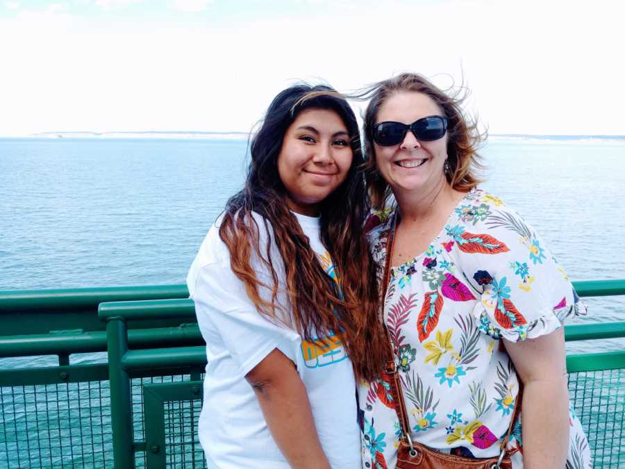 Woman poses with her adopted daughter by the water 