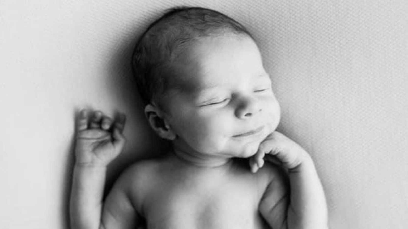 Newborn baby boy smiles in his sleep