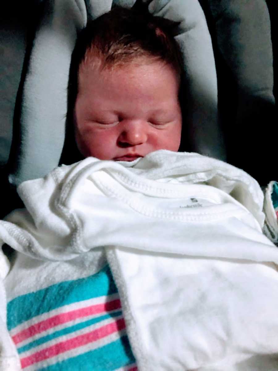 Newborn baby boy sleeps in a car seat after going home with foster parents