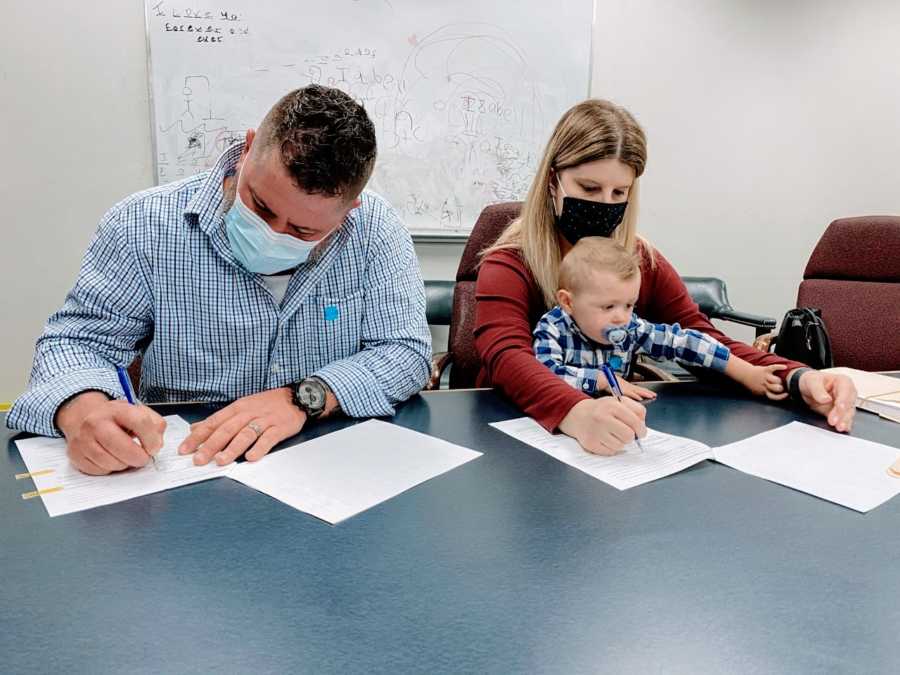 Foster parents sign paperwork to adopt the little boy they had been fostering