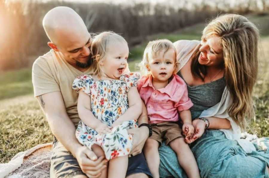 Family of four take beautiful family photo during an outside photoshoot at golden hour