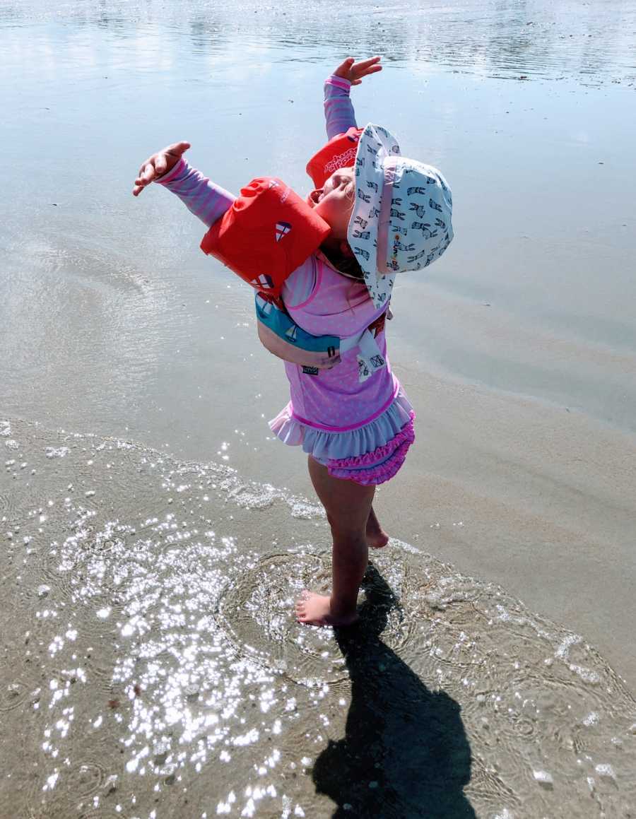 Little girl with Down syndrome dances around and relishes the sunshine while at the beach