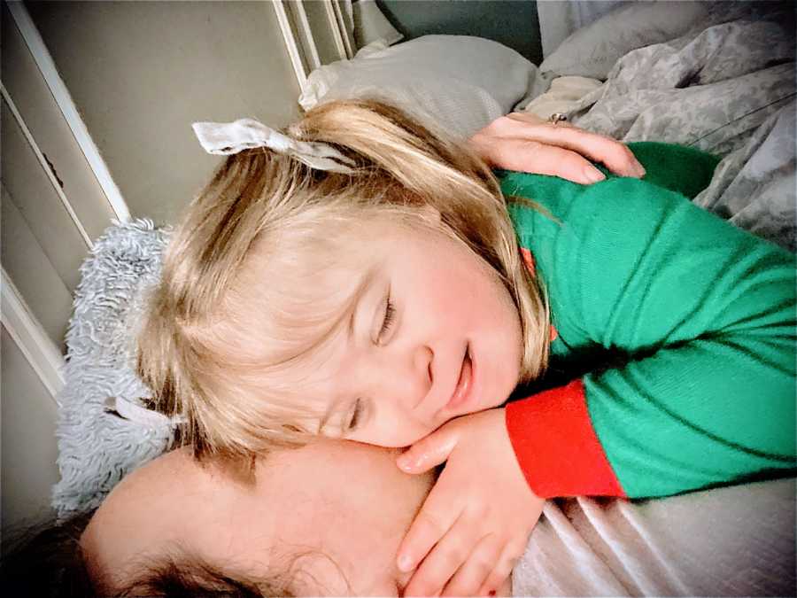 Little girl with Down syndrome smiles and cuddles with her dad at Christmastime