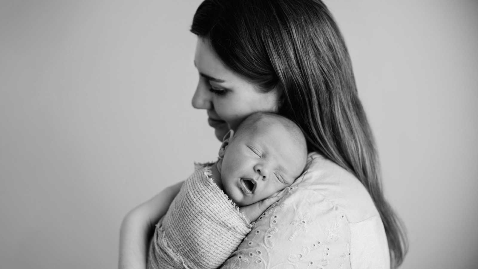 First time mom snuggles her sleeping newborn son during a photoshoot