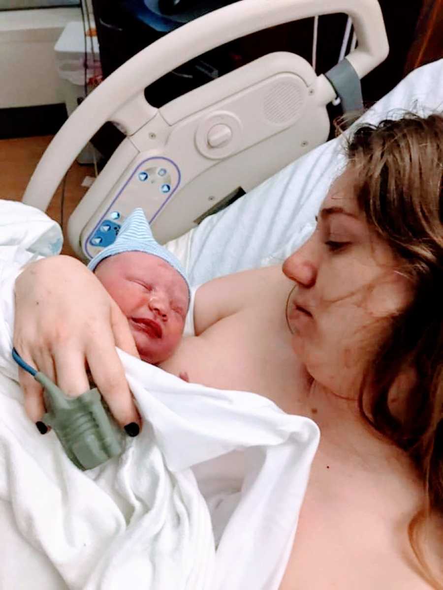 Woman looks down at her newborn after giving birth with a look full of love