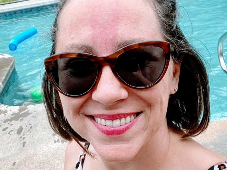 Woman in sunglasses takes a bikini selfie by the pool