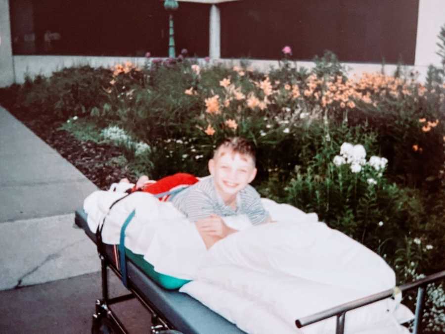 Little boy recovering from Dorsal Rhizotomy smiles for the camera while out in the garden at a hospital