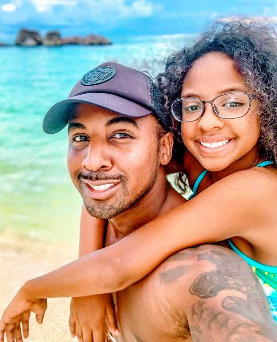 Single dad takes a selfie with his daughter on his back while at the beach