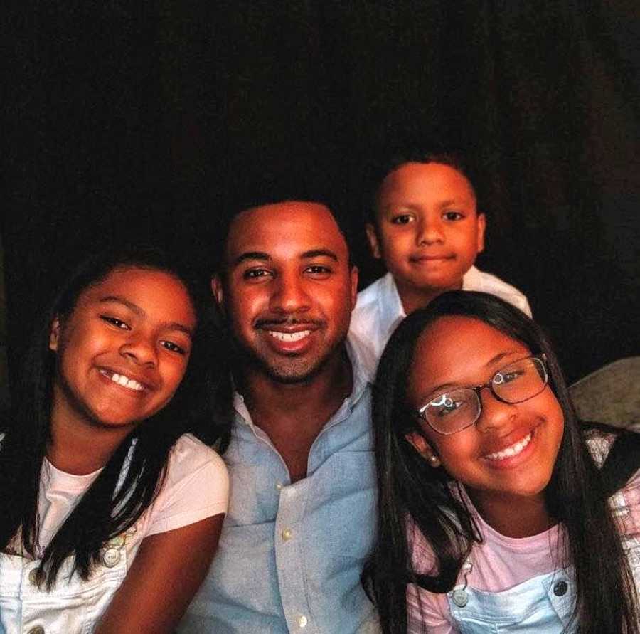 Single black dad poses for a family photo with his three kids