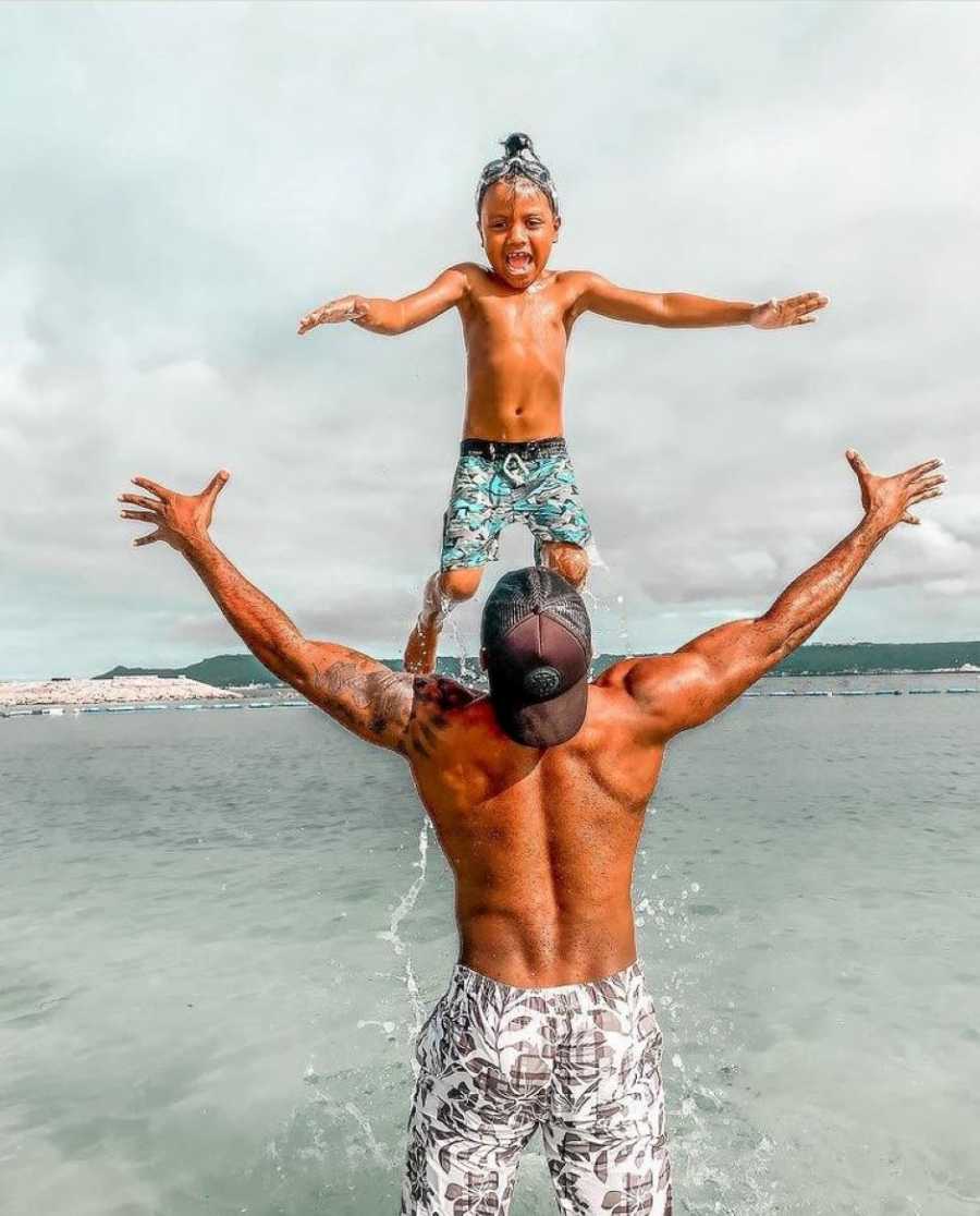 Single dad throws his son up into the air while having a beach day