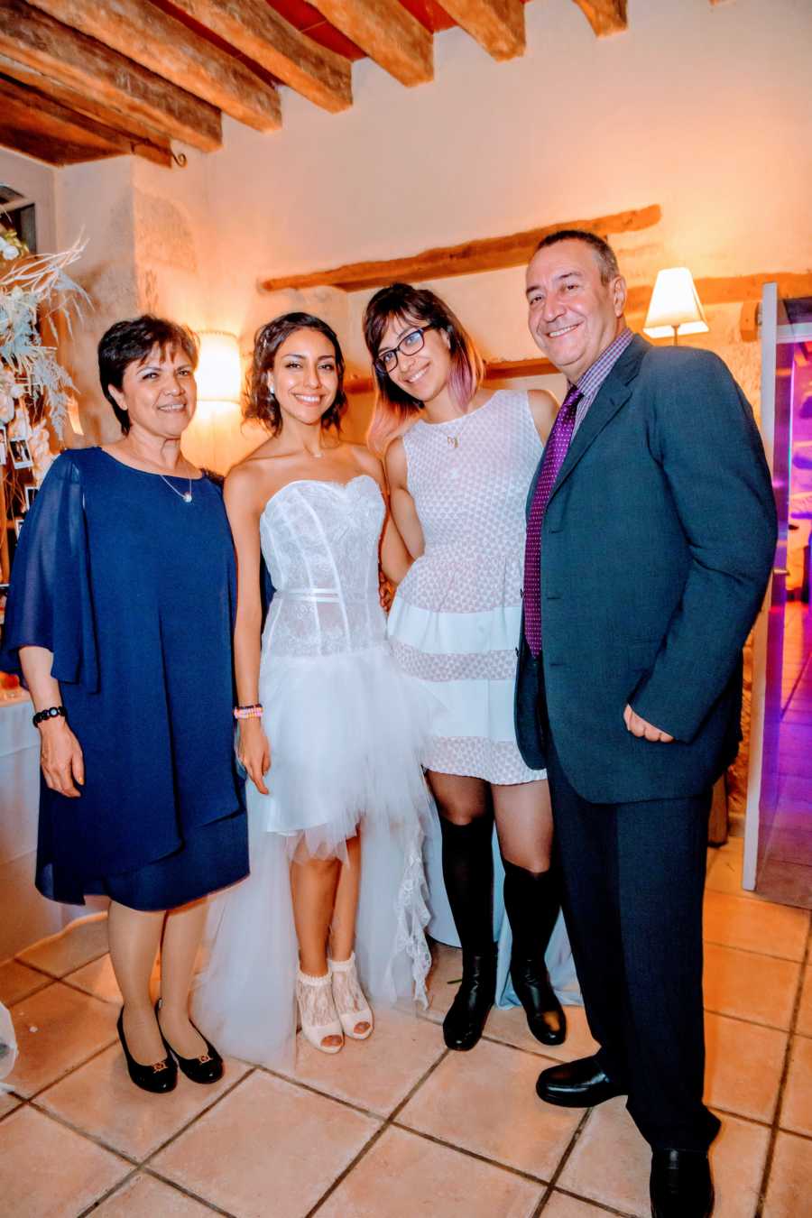 Woman takes a family photo with her parents and younger sister at her wedding reception