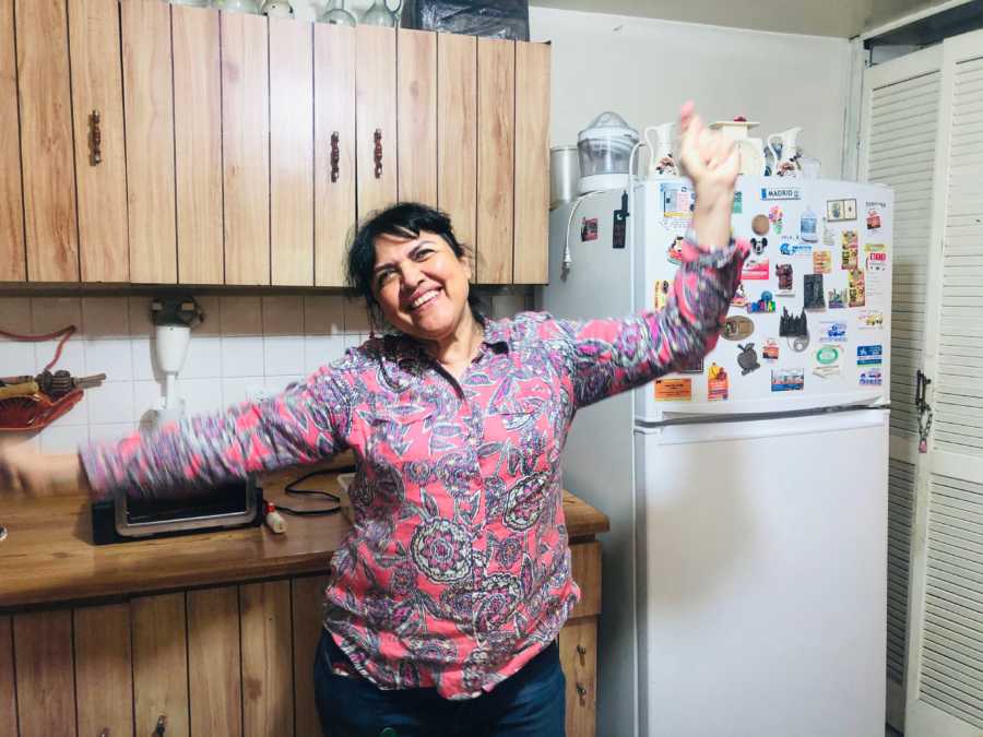 Woman snaps a photo of her mom looking happy while dancing and smiling in the kitchen