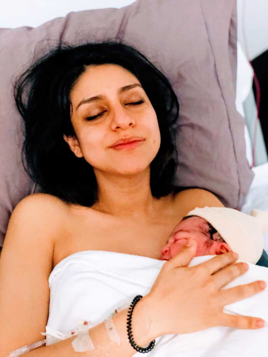 Woman cuddles her newborn baby girl after 20 hours of labor