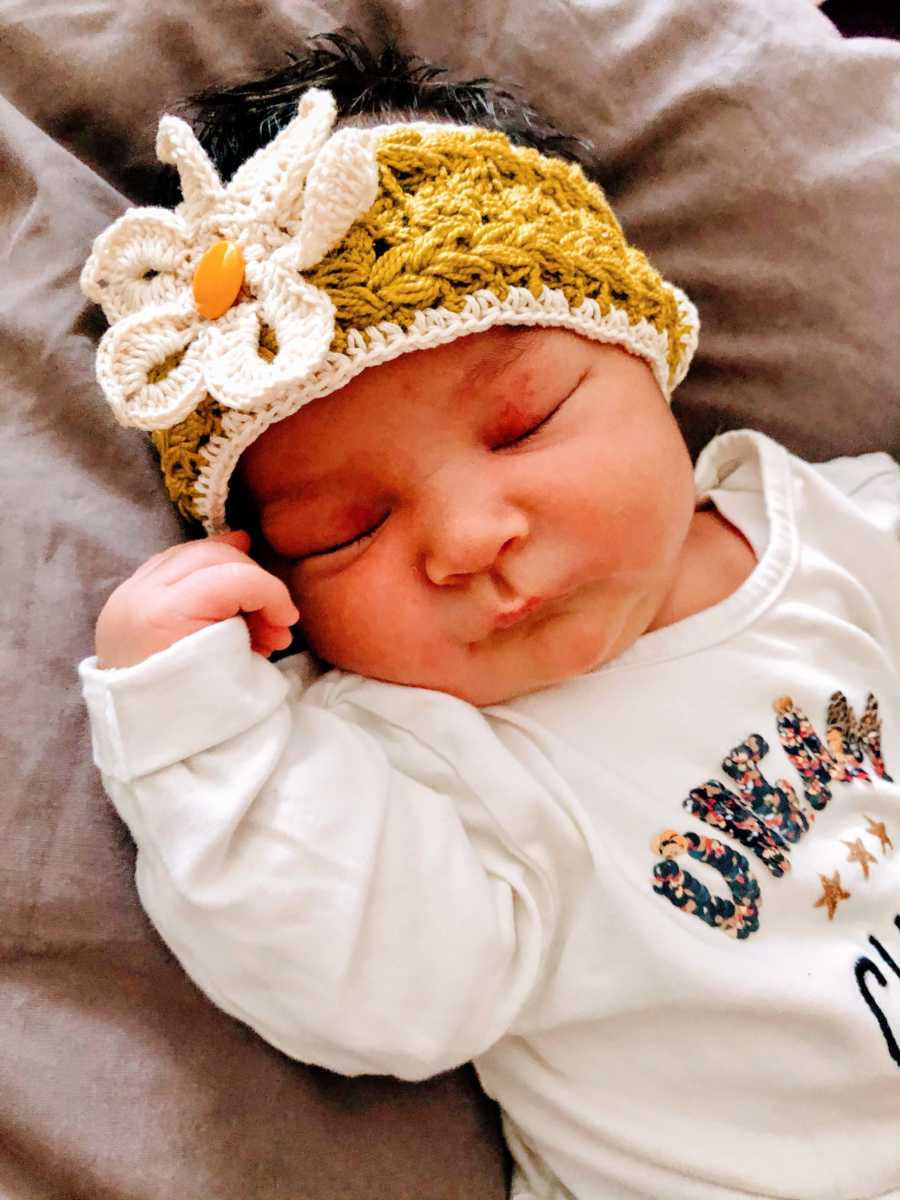 New mom snaps a photo of her newborn baby girl with a crocheted flower headband on